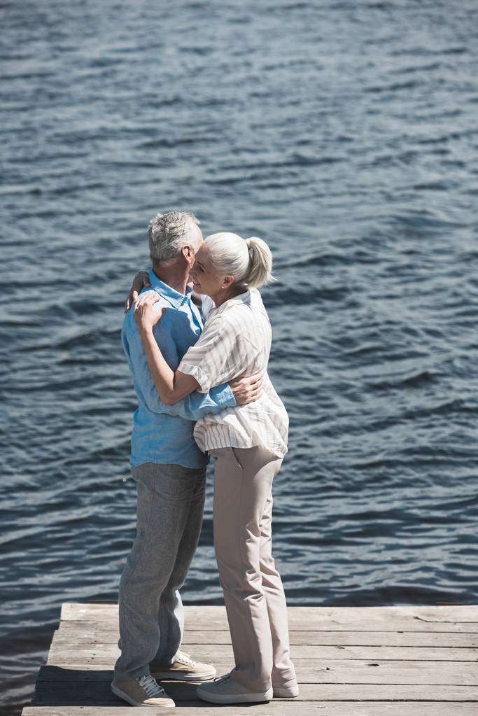 couple aux cheveux gris étreignant sur le bord de la rivière
 - Photo, image
