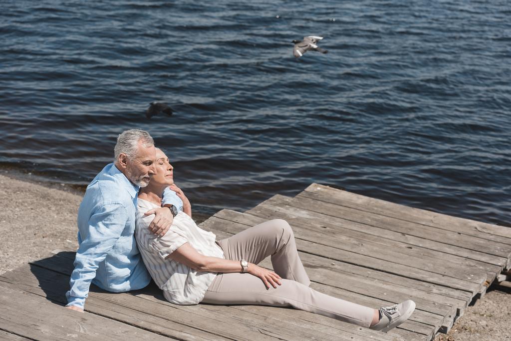 casual ηλικιωμένο ζευγάρι χαλαρώνοντας στο riverside - Φωτογραφία, εικόνα