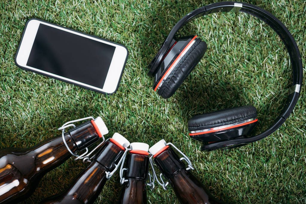 Bierflessen met smartphone en hoofdtelefoons - Foto, afbeelding