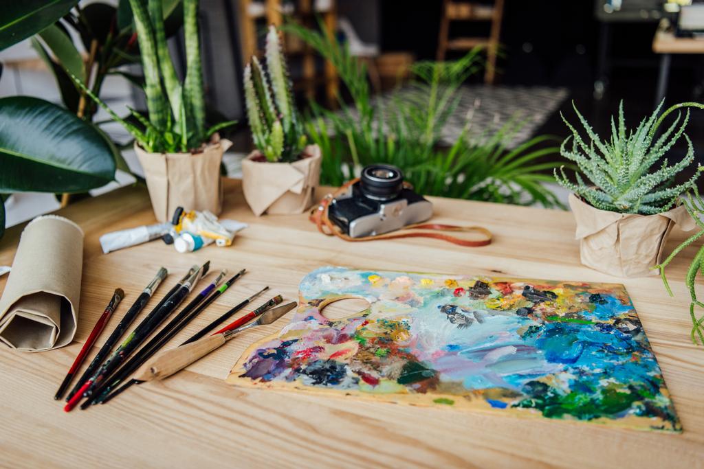 Зеленые растения с предметами искусства на столе
 - Фото, изображение