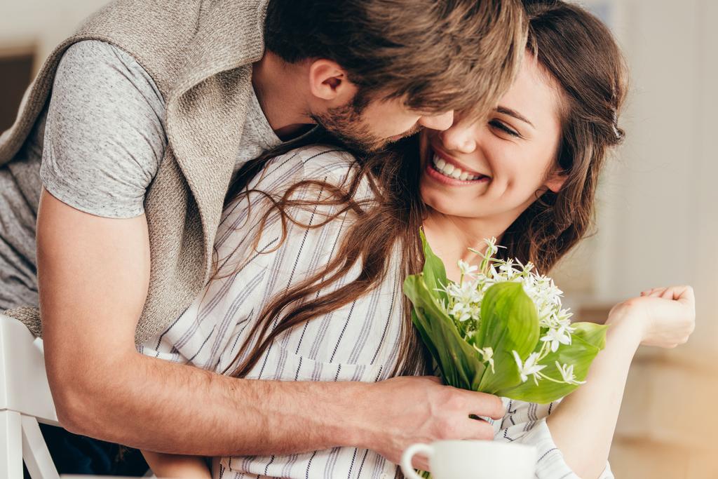 junges Paar umarmt sich mit Blumenstrauß - Foto, Bild