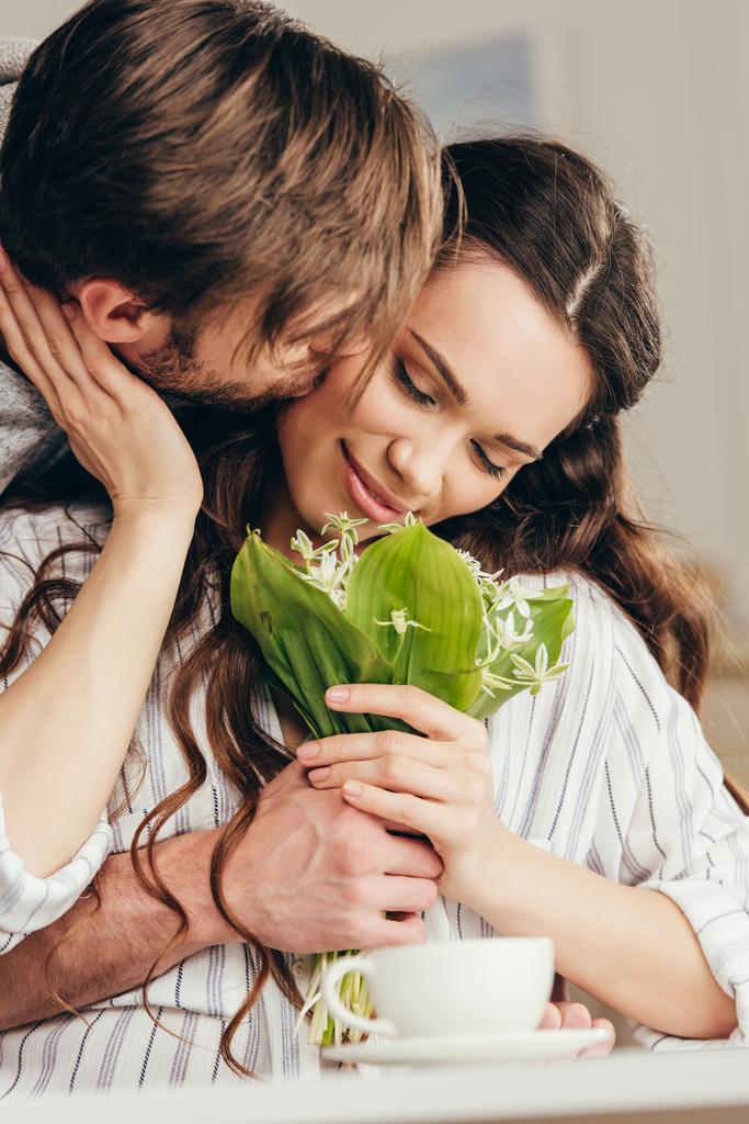 couple embracing and kissing with bouquet of flowers - Photo, Image