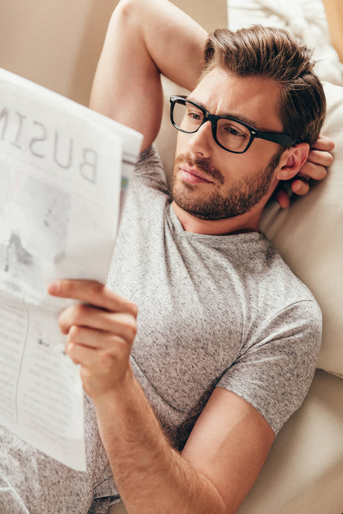 νεαρός άνδρας διαβάζει εφημερίδα στο σπίτι - Φωτογραφία, εικόνα