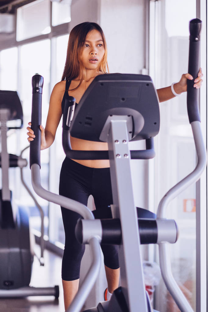 Young petite woman exercising on ski machine in the gym - Photo, Image
