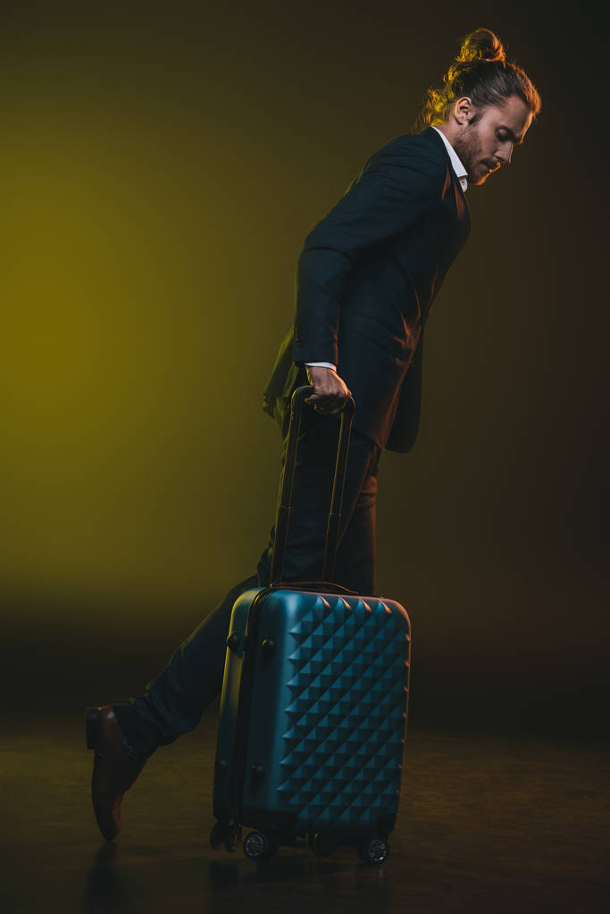 bavulla yürüyüş takım elbiseli genç adam - Fotoğraf, Görsel