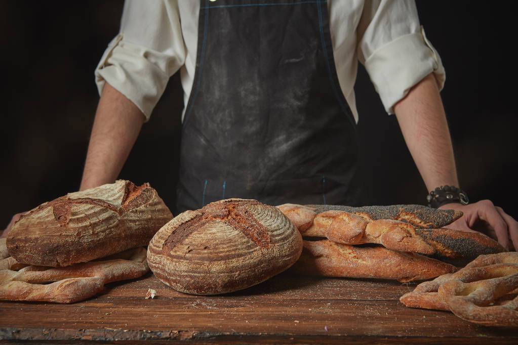 пекарь в фартуке со свежим хлебом
 - Фото, изображение