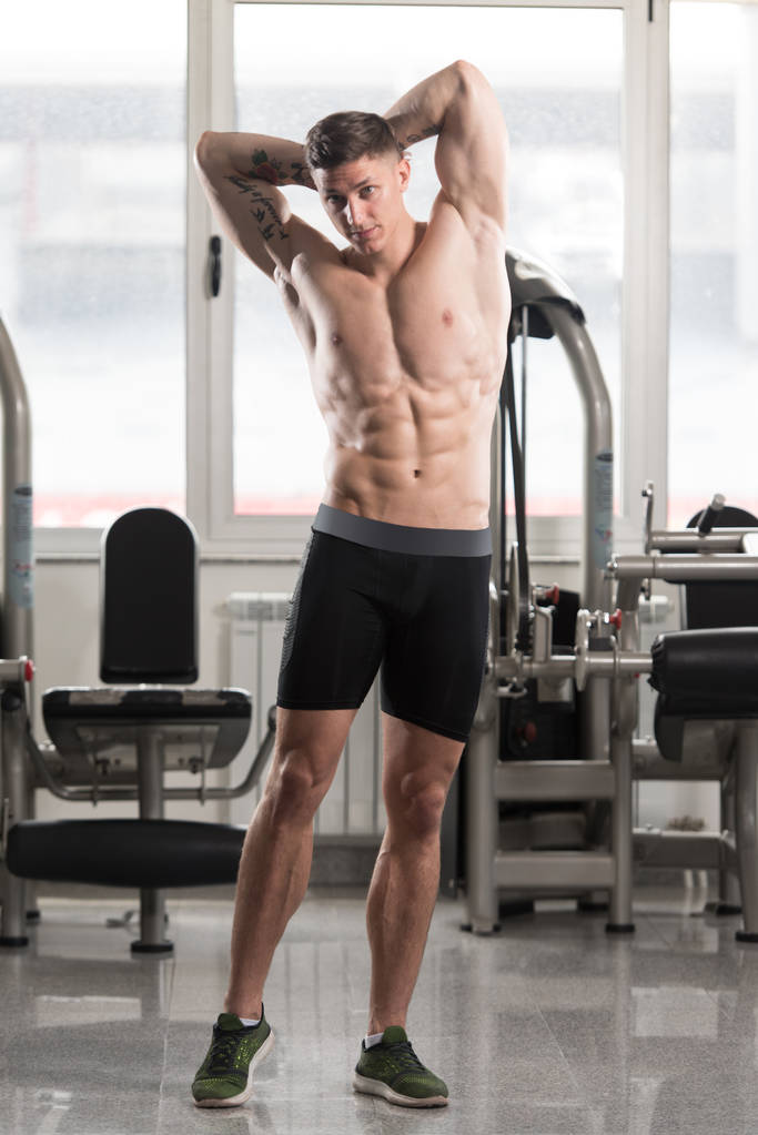 Musculoso hombre flexionando los músculos en el gimnasio
 - Foto, imagen