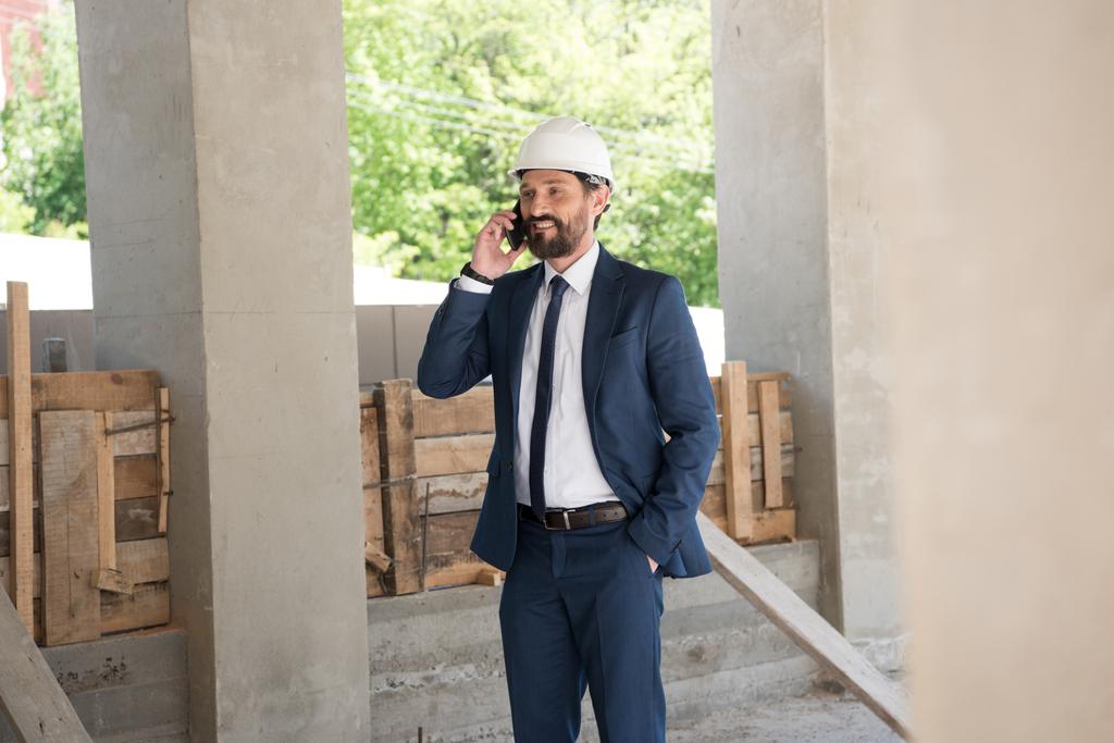 lachende aannemer praten op smartphone op bouw - Foto, afbeelding