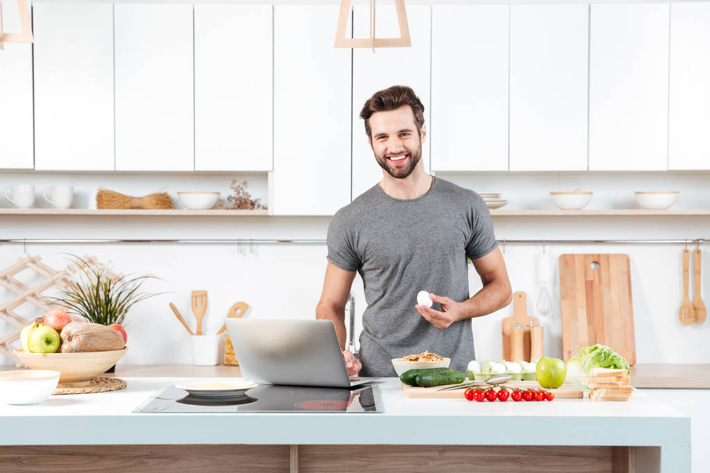 Attractive young man cooking with mixing bowl - Photo, Image