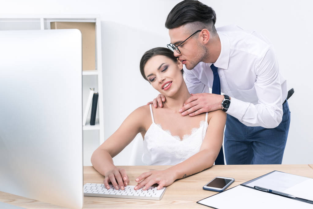 businessman whispering to beautiful colleague at office - Photo, Image