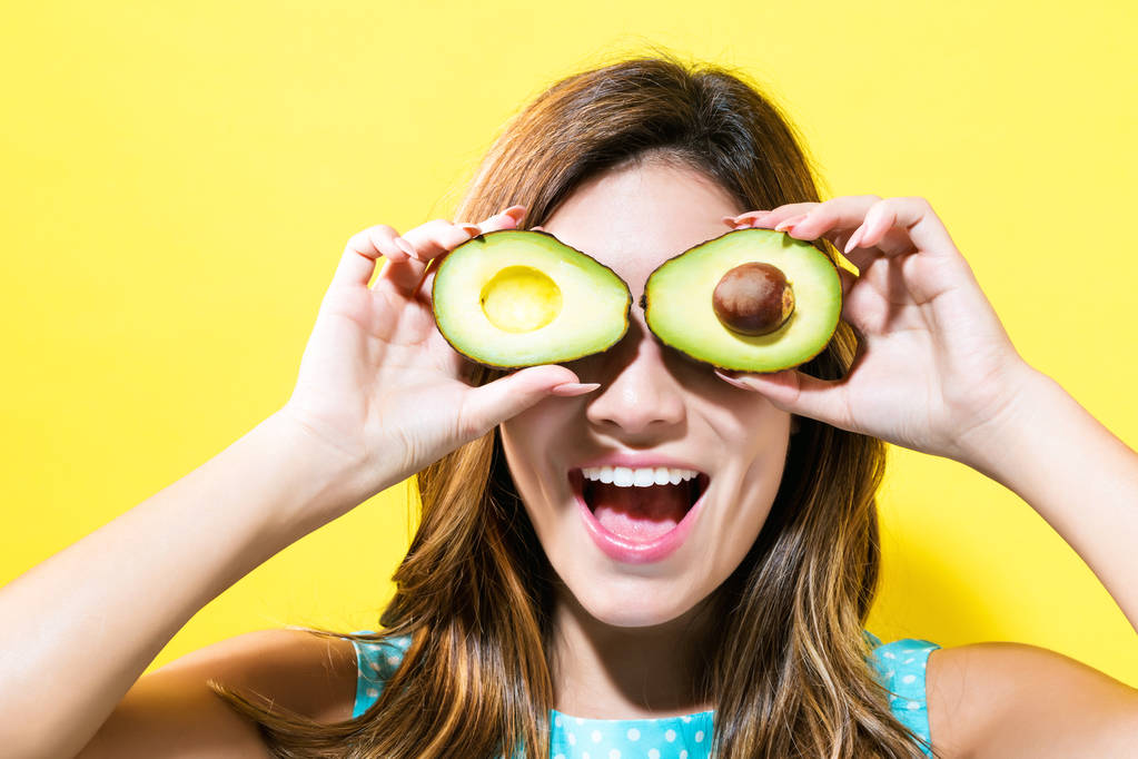 Щаслива молода жінка тримає половинки авокадо
 - Фото, зображення