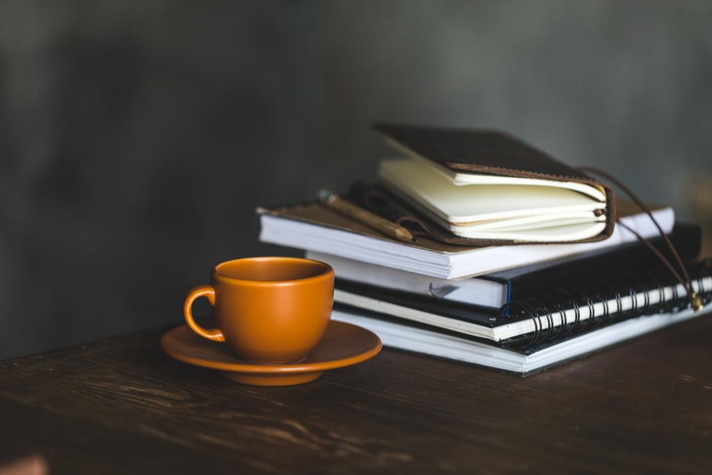 Bliska filiżankę kawy i notebooków na drewniany blat - Zdjęcie, obraz