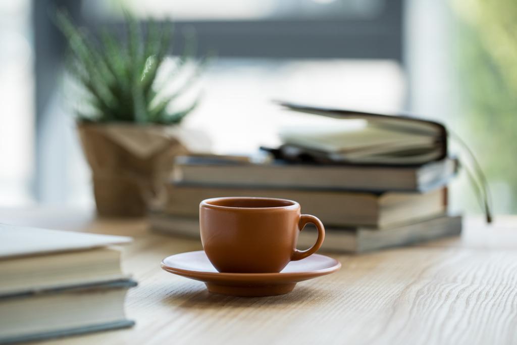 Close-up view of cup of coffee and notebooks on wooden table top - Photo, Image