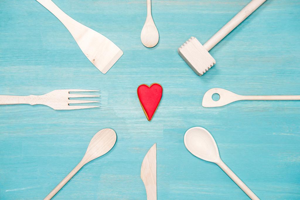 vista dall'alto di vari utensili da cucina in legno con simbolo del cuore sul tavolo blu
 - Foto, immagini