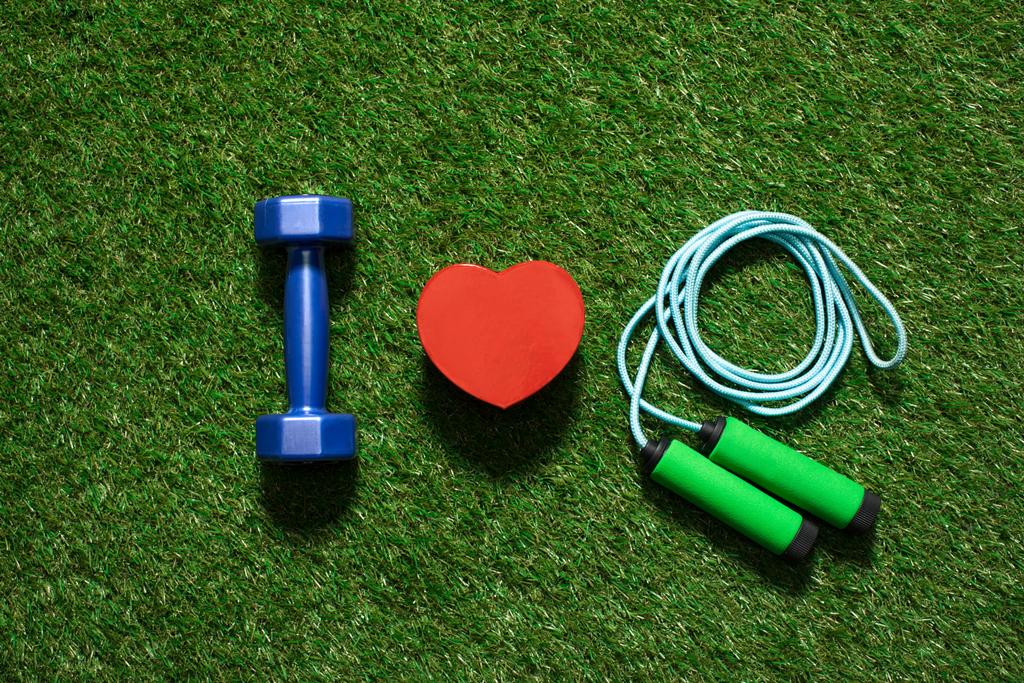 top view of colorful dumbbell with heart symbol and skipping rope on the grass - Photo, Image