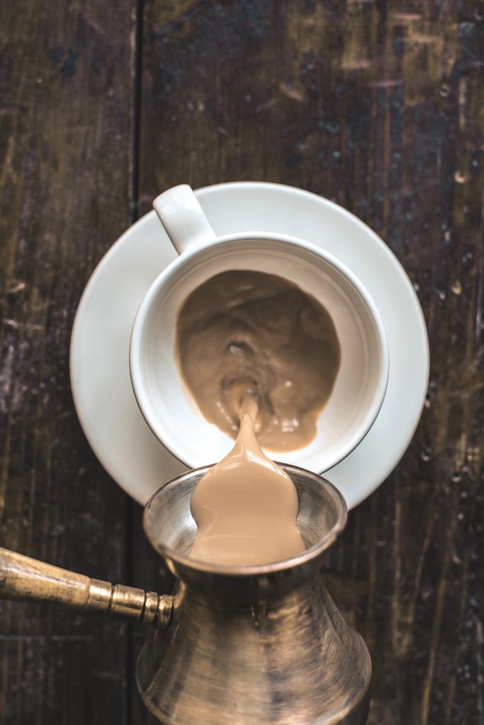 наливая кофе из cezve в чашку на стол
 - Фото, изображение