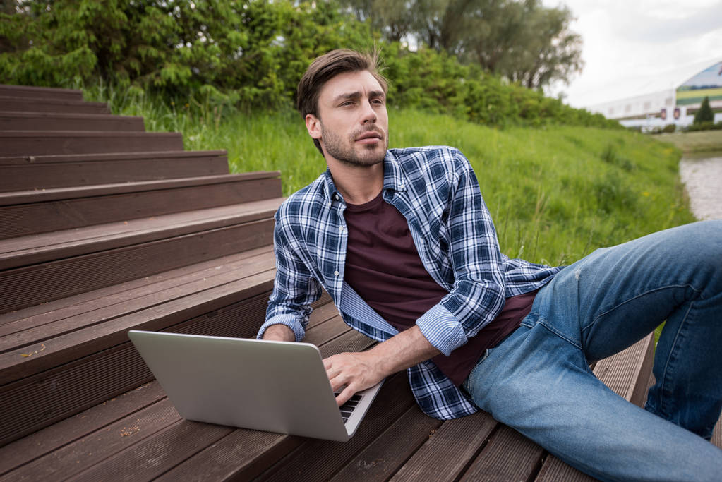 Casual man met laptop op park - Foto, afbeelding