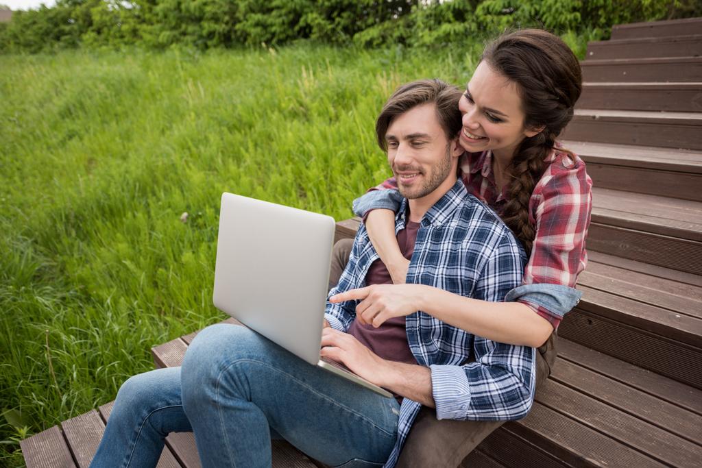 pareja usando portátil mientras está sentado en el parque
 - Foto, Imagen
