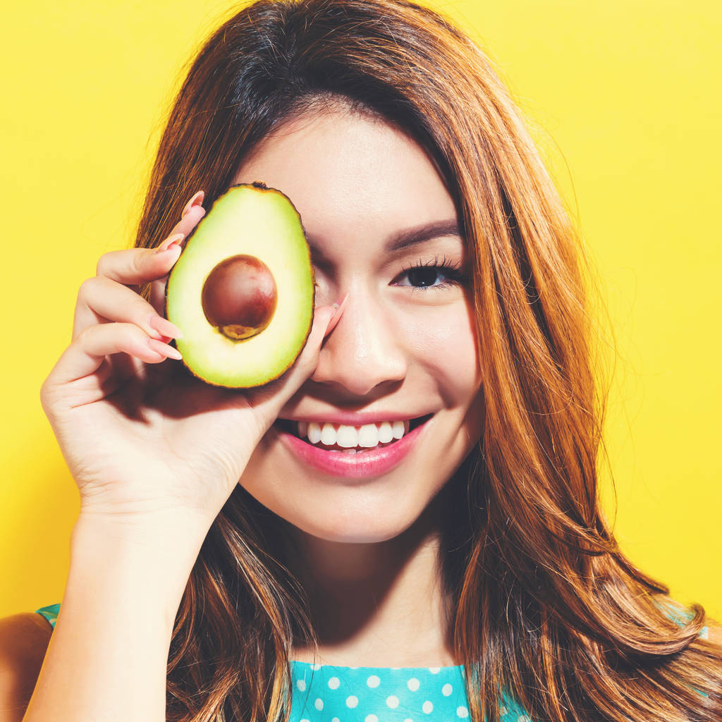 Gelukkig jonge vrouw bedrijf avocado halveren - Foto, afbeelding