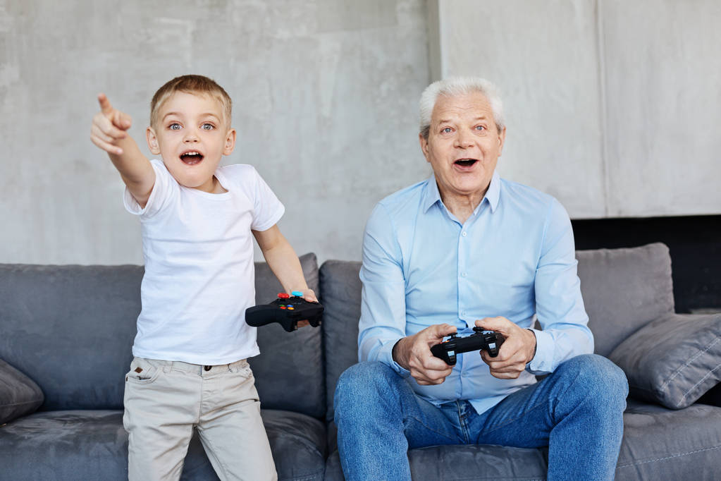 子供とおじいちゃんが一緒にビデオゲームをプレイ - 写真・画像