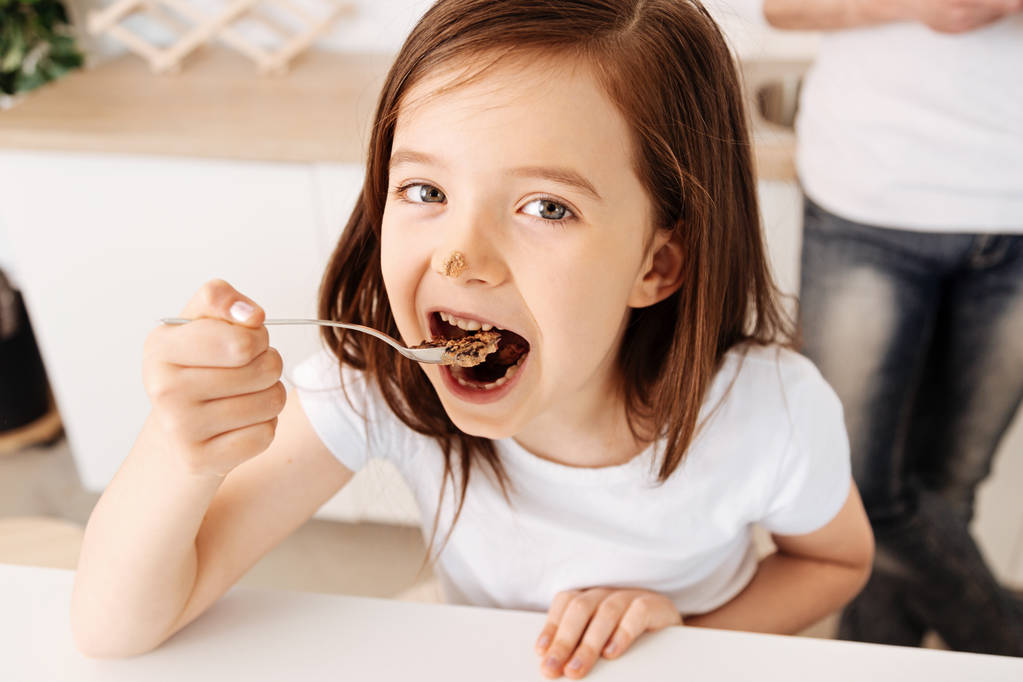 Досить маленька дівчинка їсть шоколадний торт
 - Фото, зображення