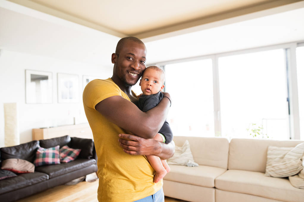 Молодий афроамериканський батько тримає свого сина в руках
 - Фото, зображення