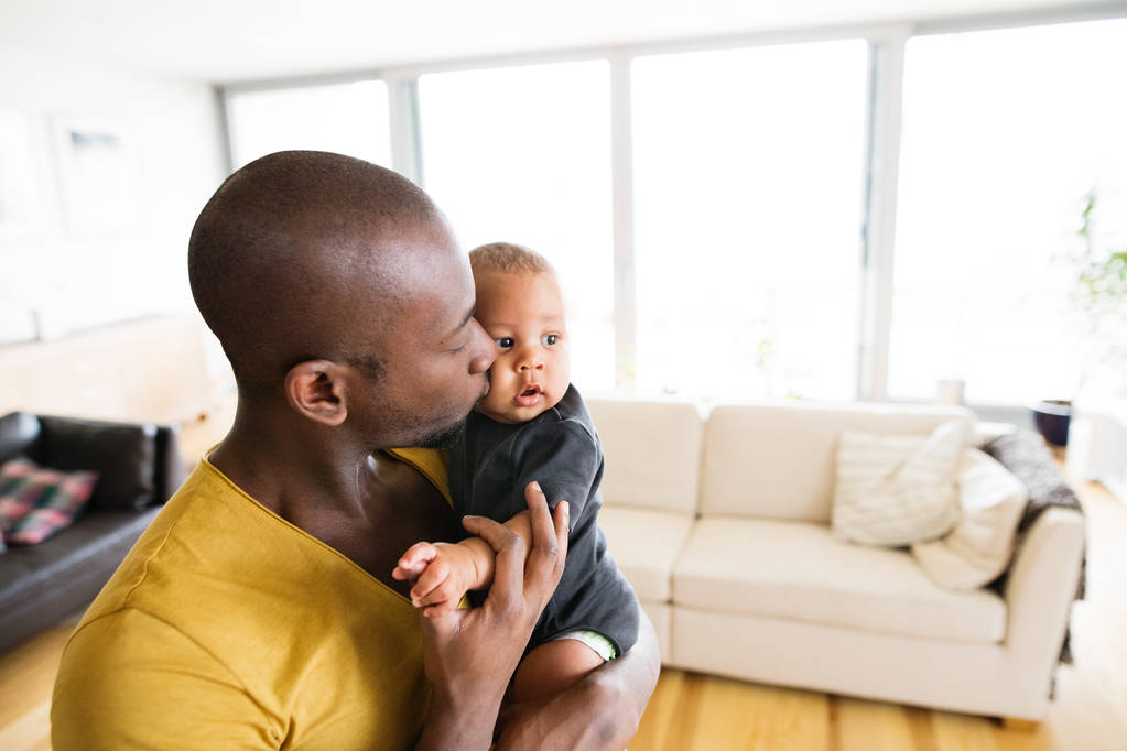 Joven padre afroamericano sosteniendo a su hijo en brazos
 - Foto, Imagen