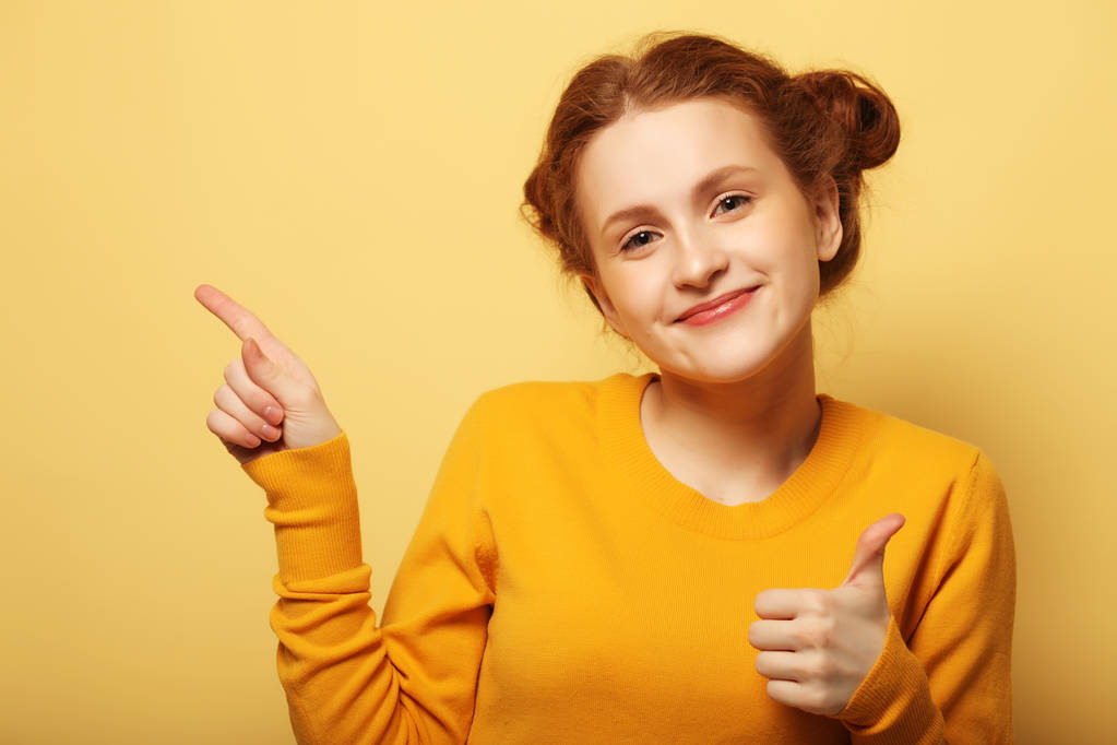 Retrato de una chica bonita apuntando con el dedo sobre el bac amarillo
 - Foto, Imagen