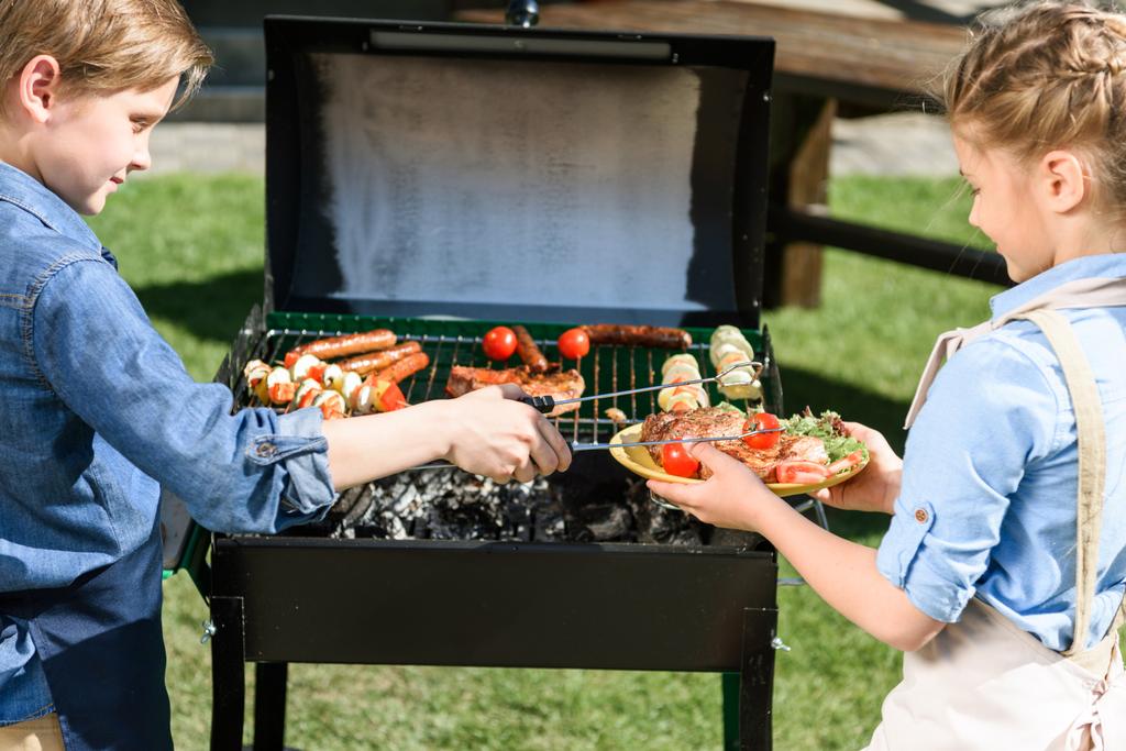 lapset valmistavat lihaa ja vihanneksia grillillä
 - Valokuva, kuva