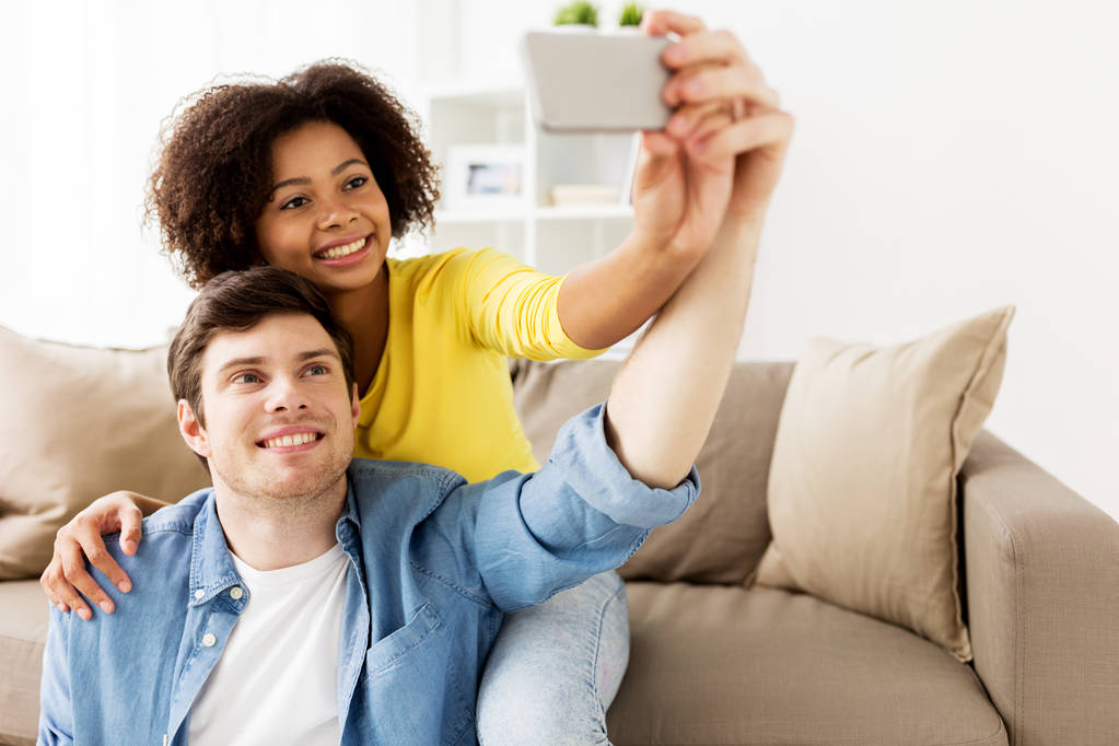 szczęśliwa para z smartphone biorąc selfie w domu - Zdjęcie, obraz