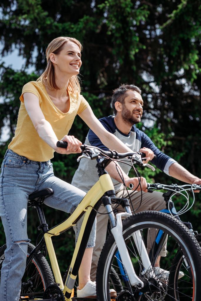 усміхнена пара їде на велосипедах у парку
 - Фото, зображення