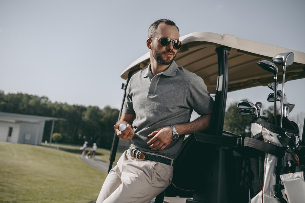 stijlvolle golfer holding golfbal - Foto, afbeelding