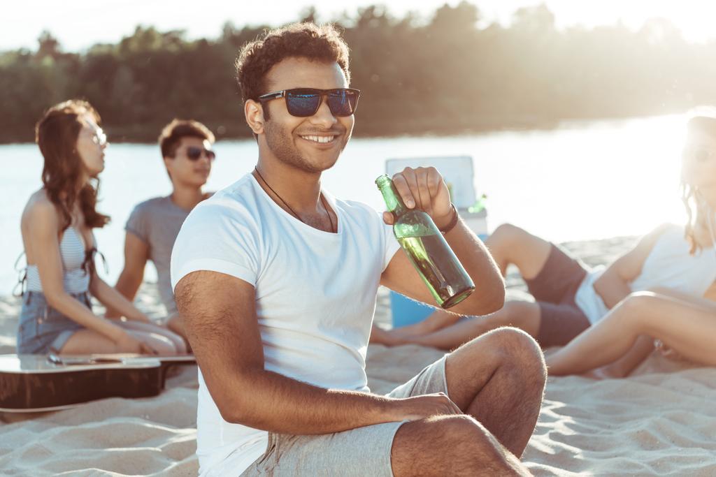 jongeman bier drinken op strand - Foto, afbeelding