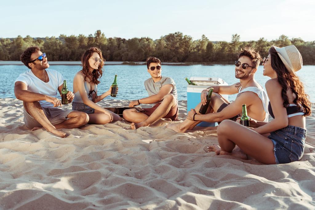 друзья пьют пиво, расслабляясь на берегу реки
 - Фото, изображение