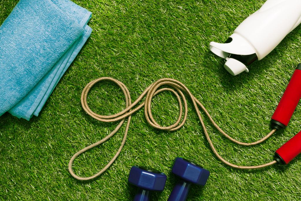 стрибати мотузкою з рушником і пляшкою на траві
 - Фото, зображення