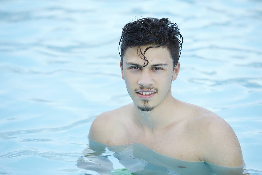 Szczęśliwy człowiek atrakcyjny stojąc w niebieska woda w basenie - Zdjęcie, obraz