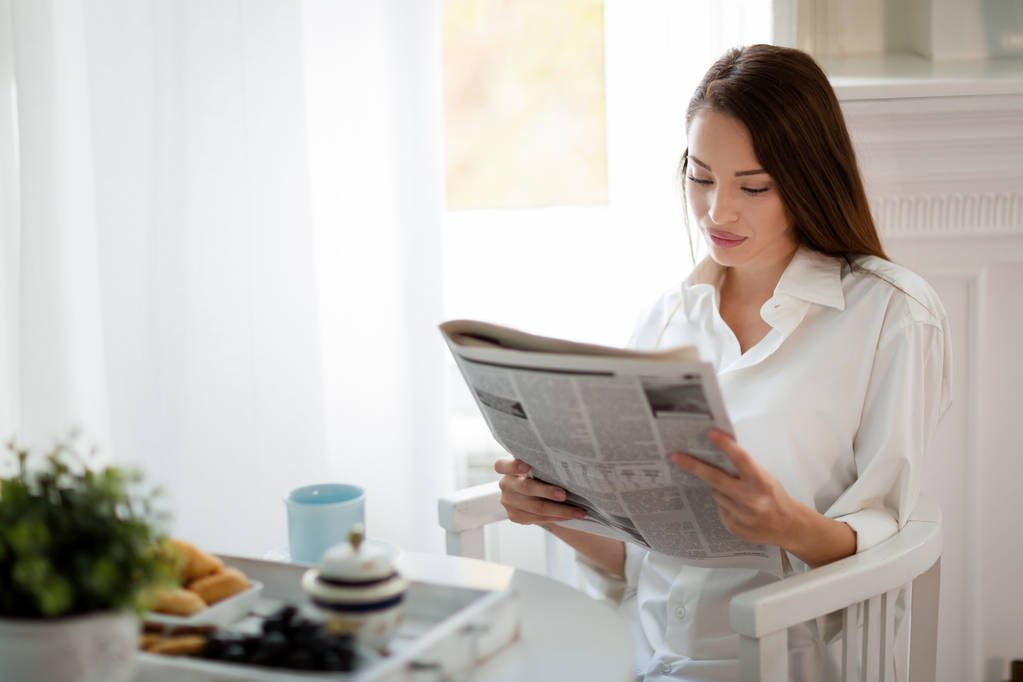 woman reading magazine at table - Photo, Image