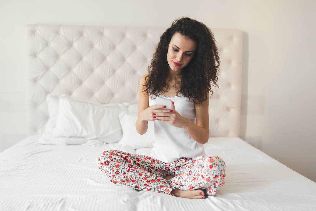 mujer usando el teléfono mientras está sentado en la cama
 - Foto, imagen