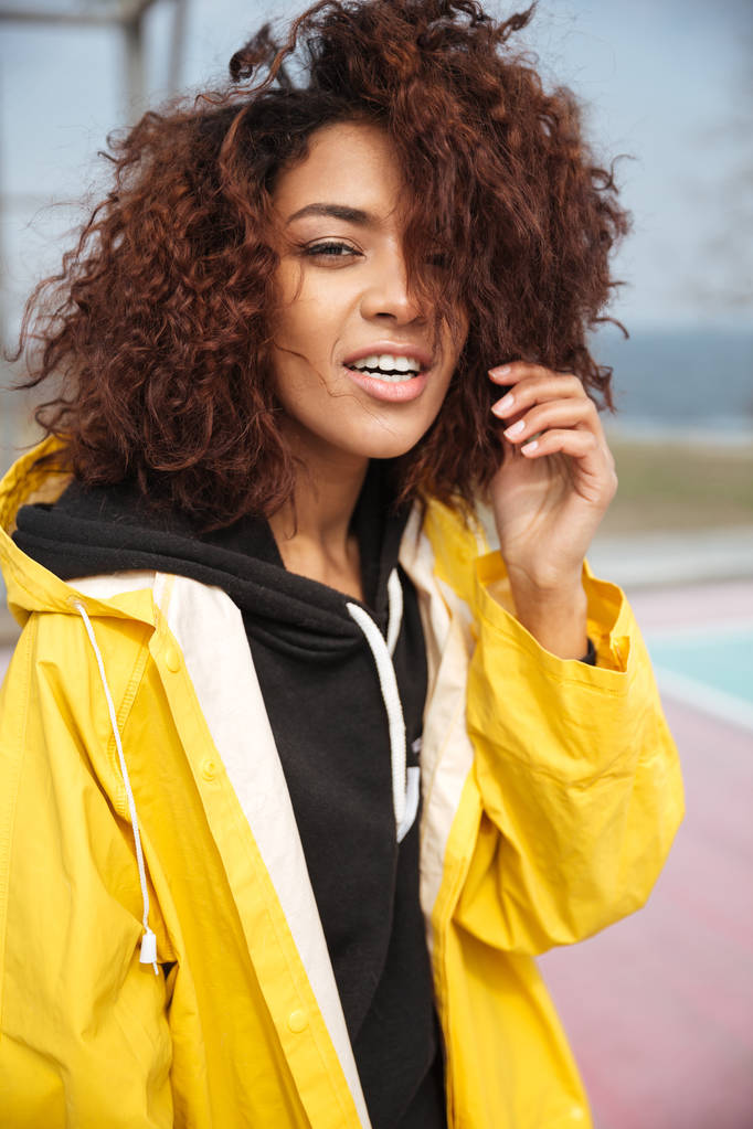 Amazing african curly young woman wearing yellow coat - Photo, Image