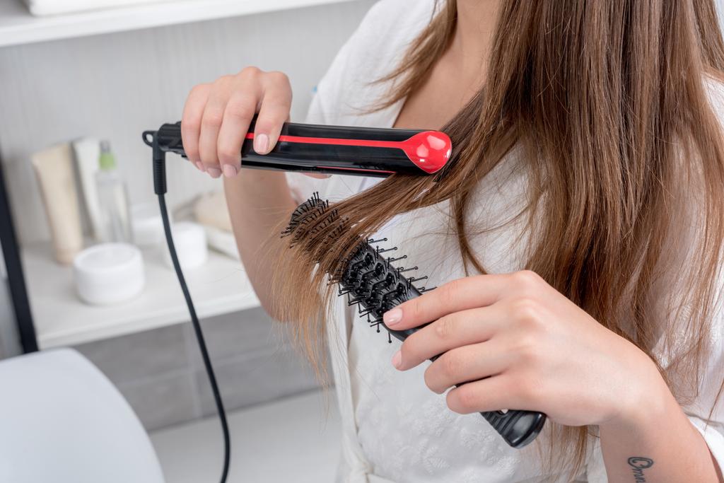 woman using hair straightener - Photo, Image