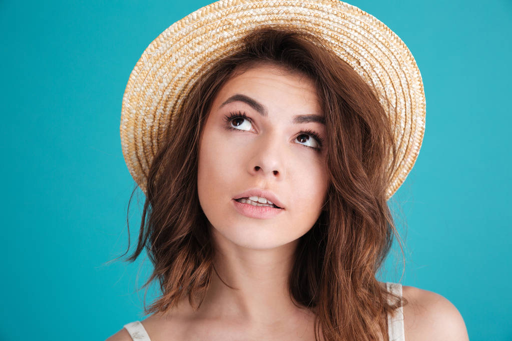 Продумана молода жінка в солом'яному капелюсі дивується і дивиться в очі
 - Фото, зображення