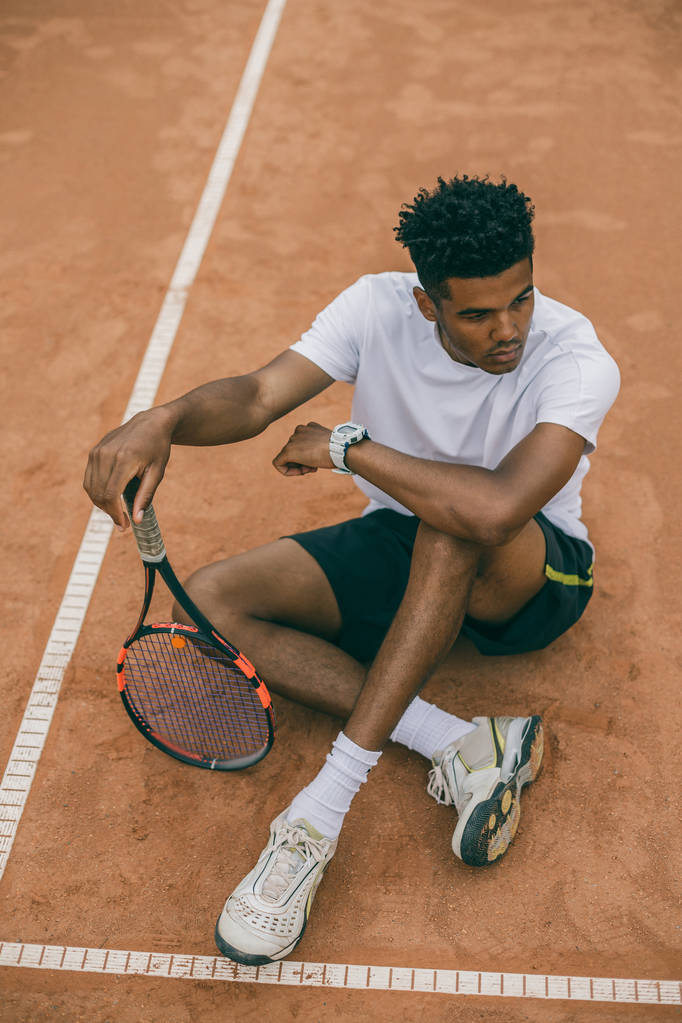 Pohled shora mladík tenista sedí na zemi tenisový kurt - Fotografie, Obrázek
