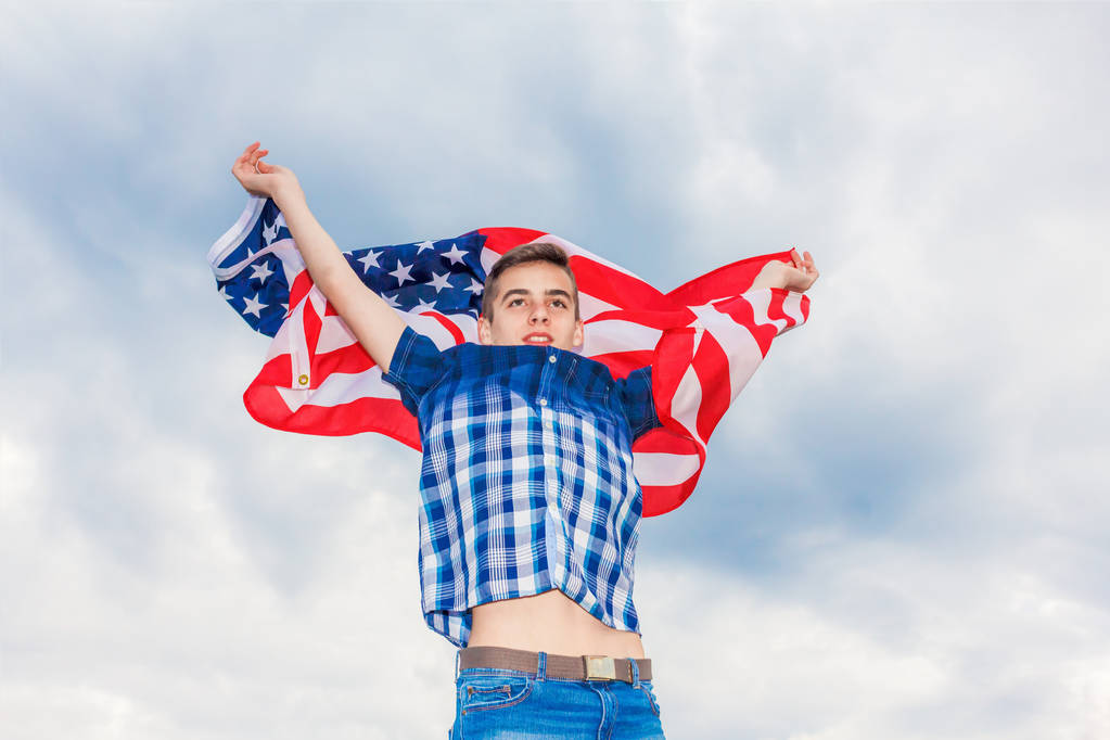 Флаг США держит бегущий парень на фоне летнего неба
 - Фото, изображение