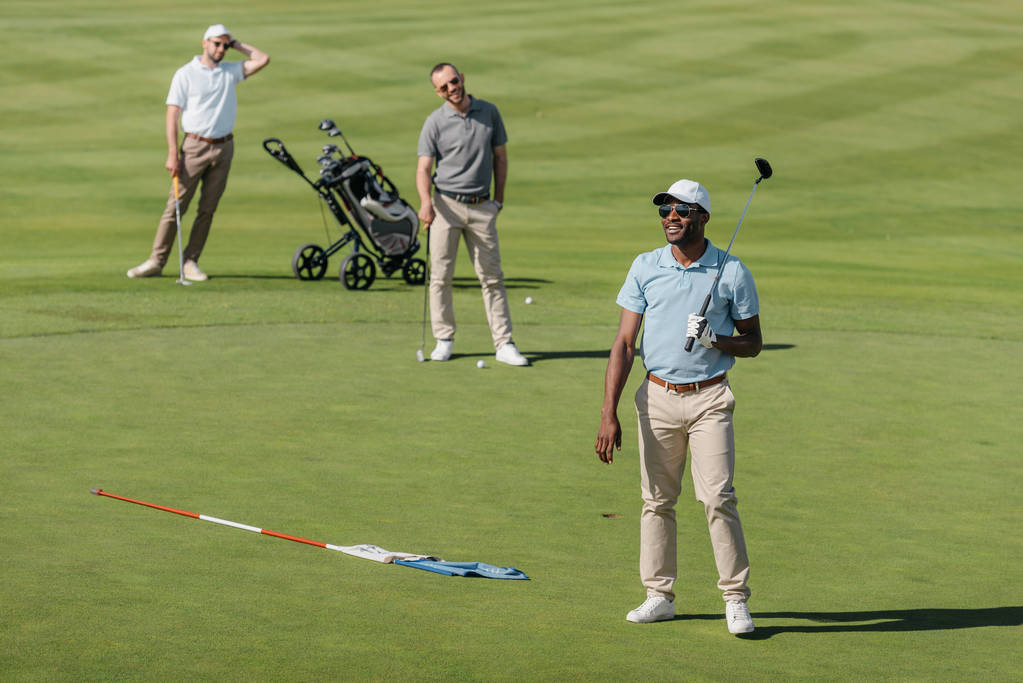 Sportler stehen mit Golfschlägern auf dem Platz - Foto, Bild