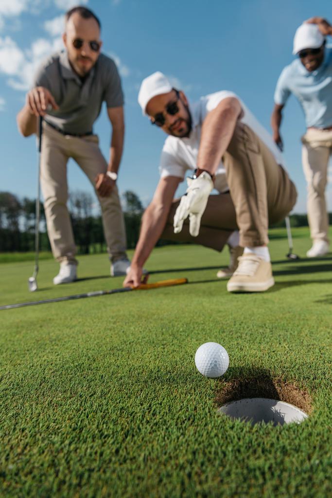 παίκτες του γκολφ που βλέπουν μπάλα κοντά τρύπα - Φωτογραφία, εικόνα