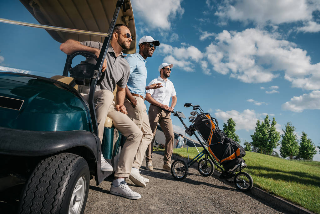 Männer stehen neben Golfwagen - Foto, Bild