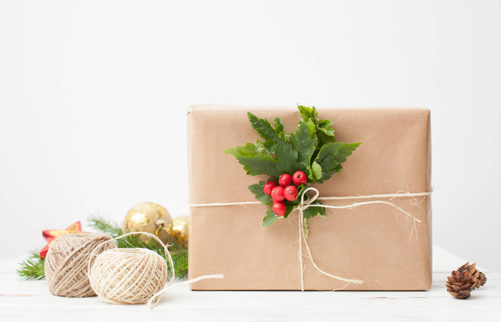 Упакований для подарунків у простому папері з гілочкою та червоними ягодами
 - Фото, зображення