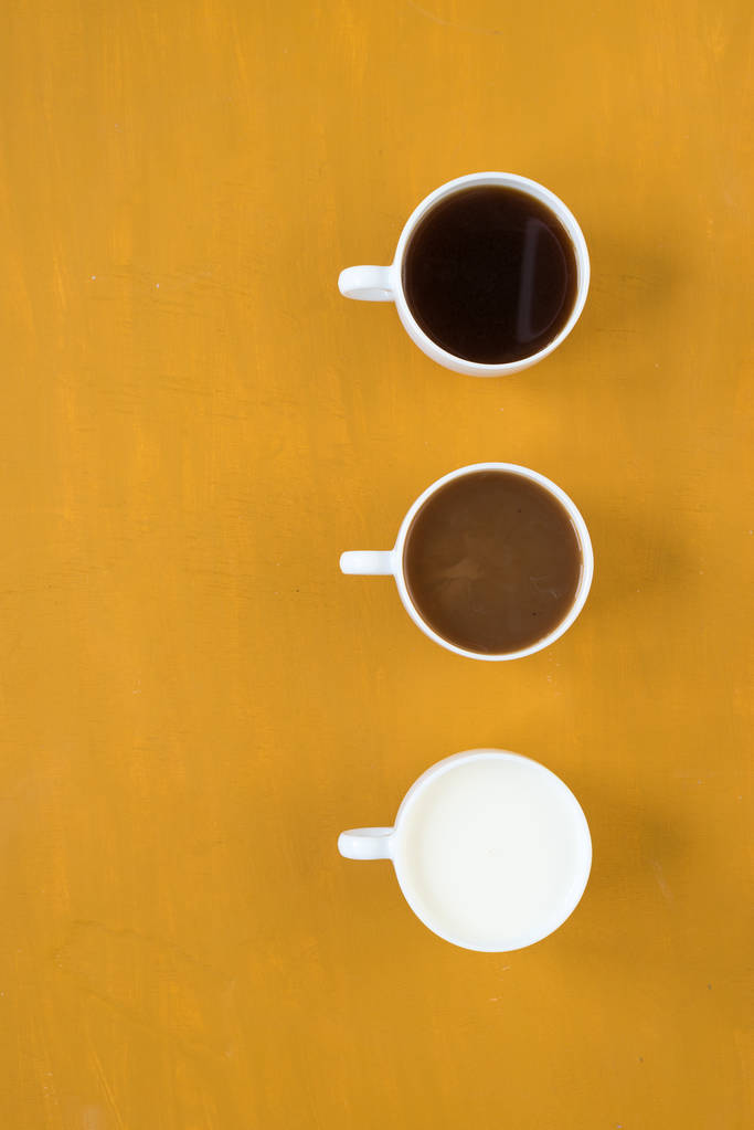 Tres tazas con café y leche sobre fondo amarillo
 - Foto, imagen
