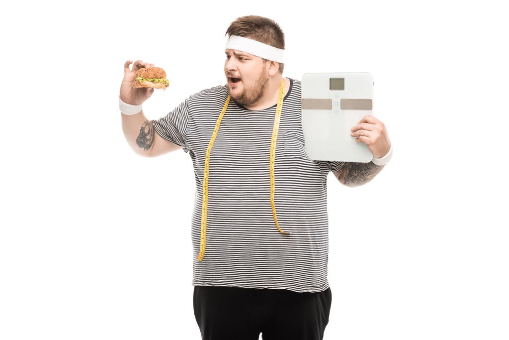 homme tenant des balances corporelles et hamburger
 - Photo, image