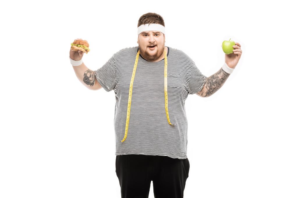 fat man holding burger and apple - Photo, Image